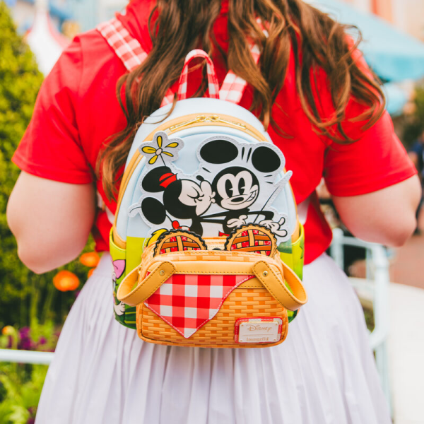 Life’s a picnic when you’re with your pals! Spend a sunny day in the countryside with the Loungefly Mickey and Friends Picnic Mini Backpack. On the front, a woven picnic basket takes shape on the bag’s zipper pocket. Look inside the basket to find a Mickey-shaped pie, which doubles as a strawberry-scented coin bag! Minnie and Mickey appear up above while Donald, Daisy, and Goofy join the fun on the bag’s side pockets. On the back, gingham shoulder straps accompany Pluto as he sizes up a tasty feast. This mini backpack makes a stylish addition to any outing and has plenty of room to pack your picnic essentials. The Loungefly Mickey and Friends Picnic Mini Backpack is made of vegan leather (polyurethane). Bag has adjustable shoulder straps, removeable coin bag (polyurethane), and shiny gold hardware. Additional features include applique, debossed, scented, and printed details. Take note of the coordinating inside lining. This backpack is an officially licensed Disney product. Backpack dimensions: 9”W x 10.5”H x 4.5”D