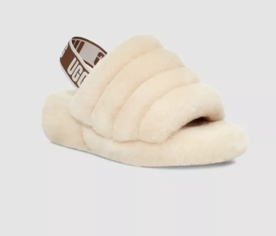The UGG Women's Fluff Yeah Slides in Natural, size 8M, blend luxurious comfort with a modern, chic design. These slides feature a plush sheepskin upper in a soft, neutral natural color, ensuring both warmth and style. The standout feature of the Fluff Yeah Slides is the wide elastic strap adorned with bold UGG branding, adding a contemporary touch while securing the foot comfortably. This design not only enhances the visual appeal but also allows for easy slip-on and off functionality. Inside, these slides are lined with soft sheepskin that provides exceptional comfort and temperature regulation, making them suitable for year-round wear. The footbed is cushioned to offer support and comfort with every step. Set on a lightweight platform outsole with a durable rubber bottom, these slides provide traction and stability, whether you're lounging at home or stepping out casually. The UGG Women's Fluff Yeah Slides in Natural are a versatile and stylish choice, perfect for adding a touch of luxury to your everyday wardrobe.