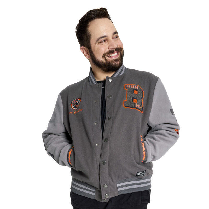 Show your allegiance in stealth style with our Loungefly COLLECTIV STAR WARS™ Rebel Alliance™ VRSITY Jacket. This fashionable jacket features discreet callouts to your favorite fandom. Elevated details, such as embroidery and chenille patches, add varied textures and an elegant flair. At the top, there’s a chenille patch “R” with orange Rebel X-Wings™. Another patch at the top features the Rebel Alliance helmet, with “Red-Five” embroidered below. The sleeves are color-blocked, with chenille patches displaying the embroidered Rebel Alliance logo in orange, along with Rebel X-Wings. Custom-molded metal snaps, down the front, feature the Rebel Alliance symbol as well. Screen printing, at the pocket openings, adds a touch of color in a motif consisting of the STAR WARS logo and Rebel Alliance symbol. On the back, the embroidery in orange says “Rebel” in Aurebesh, and embossed art of the Rebel Alliance symbol makes a grand encore appearance. The Loungefly COLLECTIV STAR WARS Rebel Alliance VRSITY Jacket is made of 100% for the outer shell and lining. Other features screen printing, chenille patches, embroidery, custom-molded metal buttons, and stiped knit band. Take note of the coordinating inside lining. This jacket is an officially licensed STAR WARS product. Comes in unisex sizes S through 3X. Sizing is very specific, so please consult the size chart before purchasing.