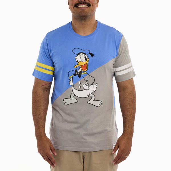 Head out to sea in great company! Gather your crew and set sail in style. This commemorative, crewneck, short-sleeved shirt features Disney’s Donald Duck in both grayscale and in color. The color scheme for this tee shirt splits on a diagonal so that the upper half of Donald Duck is in color, and the lower half is in grayscale. One sleeve carries a grayscale print with white stripes, and the other is in color, with yellow stripes. The artwork continues on the back, where you’ll encounter a tail-feathered view of Donald Duck in the same diagonal split of color and grayscale. Make waves while celebrating Donald Duck’s 90th anniversary in character. This tee features a screen print and is made of 100% cotton jersey. This tee is an officially licensed Disney product. Comes in unisex sizes S through 3X. Sizing is very specific, so please consult the size chart before purchasing.