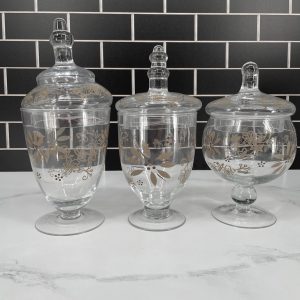 The Temp-tations Classic Set of 3 Glass Kitchen Apothecary Jars in Taupe offers a stylish and practical solution for organizing your kitchen. These elegant jars are made from durable glass, providing a clear view of their contents while adding a touch of sophistication to your countertop or pantry. The taupe color gives them a modern, neutral look that complements various décor styles. Each jar features an airtight lid to keep contents fresh and protected from moisture. Perfect for storing ingredients like sugar, flour, coffee, or even small kitchen tools, this set brings both functionality and charm to your culinary space.