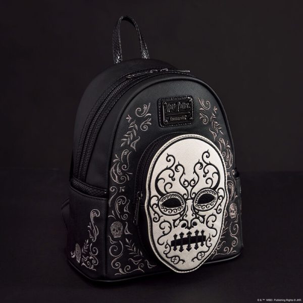 Heading to Malfoy Manor for an important meeting? Do so in style with our Harry Potter™ Death Eater Mini Backpack. This wickedly fashionable accessory features an oval-shaped front pocket with a Death Eater’s face that comes to life in applique, silver metallic vegan leather, and embroidered detail. Elegant flourishes appear on the main part of the backpack, just behind the front pocket, and they continue on the side panels. On one side panel, you will find the image of a serpent, and on the other, a skull. Turn the backpack around, and the incantation for conjuring up the Dark Mark appears: “Morsmordre.” Pack your potions, wand—or daily essentials—and take off on magical adventures in character. Features: Vegan leather (polyurethane) Padded, adjustable shoulder straps with faux snakeskin textured details Side pockets Zippered main compartment for securing items Zippered front compartment for storing smaller items Black metal hardware Applique, metallic vegan leather, embroidered, and printed details Coordinating inside lining Dimensions: 9”W x 10.5”H x 4.5”D This backpack is an officially licensed Warner Bros. product.