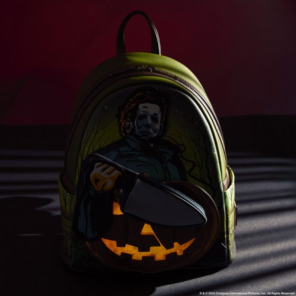 Crash the haunted hayride party looking sharp. Bring along our Halloween Mini Backpack. This accessory features Michael Myers in eerie applique detail, his form rising up over the front pocket. The front pocket is shaped like a jack-o’-lantern, and Michael Myers brandishes a knife with a reflective metallic vegan leather “blade.” This applique knife doubles as a removable coin bag for storing smaller items on your journeys. In the dark, the jack-o’-lantern’s eyes and mouth glow! The gleaming knife makes an encore appearance as a print on the back. Pack your daily essentials and stalk your favorite haunts in style. Features: Vegan leather (polyurethane) in dark green with brown trim Padded, adjustable shoulder straps in dark brown Side pockets with artwork of dark branches, grass, and barbed wire Zippered main compartment for securing items Zippered front compartment for storing smaller items Removable coin purse Gunmetal-colored hardware Applique, glow-in-the-dark, reflective metallic vegan leather, and printed details Coordinating inside lining Dimensions: 9”W x 10.5”H x 4.5”D This backpack is an officially licensed Compass International Pictures product.