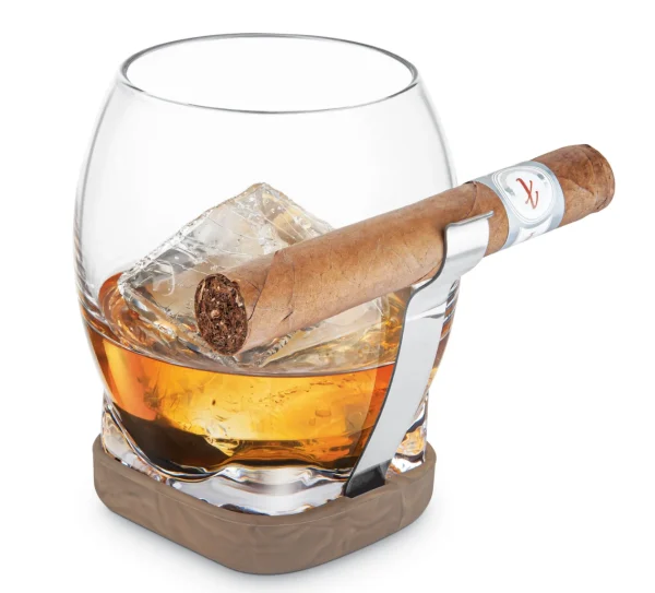 Our whiskey glass with cigar grip makes the experience even better by letting you hold your drink and cigar with one hand at the same time. Simply fill with your favourite beverage, then slide a cigar into the fully adjustable cigar grip. The cigar when inserted is held above the whiskey liquid level, which helps to prevent condensation from absorbing into the cigar. Additionally, the silicone base doubles as a non-slip coaster and the cigar grip can be removed for enjoyment without a cigar! Built-In Cigar Grip - Stainless steel grip holds the cigar securely in place by using tension and is fully adaptable to accommodate most sizes of cigars. Whiskey Glass - Uniquely shaped round bowl to help enhance aromas with a thick square glass base that provides a balanced & comfortable hand-feel while drinking. Silicone base with wood design protects surfaces from scratches & dents. Top lip of the stainless steel cigar grip is rounded off to help prevent tearing of the cigar while inserting and removing. Elevated Grip Position - Designed to hold the cigar above the whiskey liquid level, which helps to prevent condensation from absorbing into the cigar. Ideal for cigars 42-60 ring gauge size: 42 gauge: 0.66" (16.54 mm) dia.| 60 gauge: 0.94" (23.62 mm) dia. Use with and without the cigar grip.