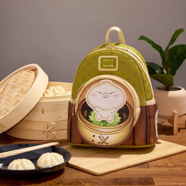 There’s nothing like a good meal to bring family together! Nurture your own little dumpling with the Loungefly Disney-Pixar Bao Bamboo Steamer Mini Backpack. On the front, a happy dumpling rests in a bamboo steamer basket on the zipper pocket while wallpaper details appear above. Turn the bag around to see soy sauce, chopsticks, and potstickers on the side pockets while a teapot appears on the bag’s back. This mini backpack has plenty of room to hold your belongings and will keep you company on all your adventures. The Loungefly Disney-Pixar Bao Bamboo Steamer Mini Backpack is made of vegan leather (polyurethane). Bag has adjustable shoulder straps and shiny gold hardware. Additional details include applique, debossed, and printed details. Take note of the coordinating inside lining. This backpack is an officially licensed Disney-Pixar product. Backpack dimensions: 9”W 10.5”H x 4.5”D