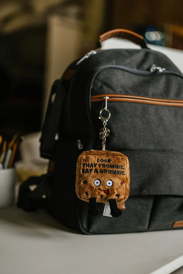 Don't be sad; this little guy thinks you're the fudging best! He knows things will get better soon, and if they don't, at least you always have brownies! His silly expression, dangly legs, and 3D chocolate chips earn him some brownie points on the cuteness scale. Head bake the perfect addition to any backpack or bag. He's the perfect gift for any brownie lover with a sweet sense of humor. This plush is ideal for children, collectors, or anyone who loves cozy and fun decor.