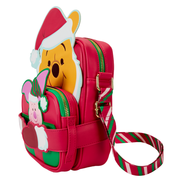 Hang the lights and pass the honey! Our Disney’s Winnie the Pooh Crossbuddies™ bag is a festively sweet way to celebrate the holidays in style. Winnie the Pooh is all decked out in a Santa hat and beard. His applique hands hug a detachable, reversible coin bag, which you can fill with a sweet treat or two. On one side, you’ll find an applique print of Disney’s Piglet, and on the other side, you’ll discover a printed applique of a beautifully wrapped honey pot gift. Piglet even makes an encore appearance as a print, inside a jar of honey. Make the season even sweeter with this fun accessory. Features: Vegan leather (polyurethane) Adjustable shoulder straps with a candy-cane striped print Detachable, reversible coin purse Gold-colored metal hardware Applique and printed details Coordinating inside lining Dimensions: 6.25”W x 8.25”H x 2.25”D